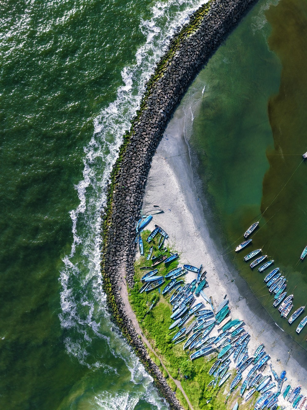 The rhythmic dance between sea and shore, where waves crash against weathered stones and boats rest in tranquil harmony.