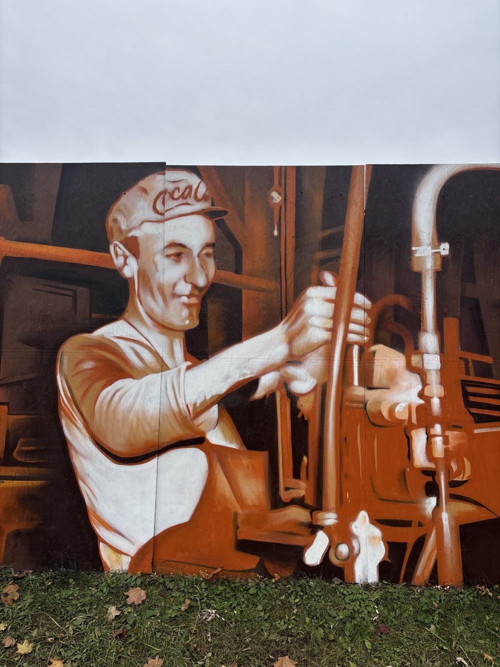 This mural explores industrial heritage and collective labor as the foundation of progress. The work combines archival imagery of workers, engineers, and machinery with the recognizable visual language of a major industrial brand, forming a unified narrative about the era of manufacturing and belief in a technological future.

The composition is structured as a continuous horizontal sequence — an analogy to an assembly line — where human effort, machines, and time operate within a shared rhythm. A cool blue-violet color palette emphasizes the technical nature of the scene while introducing a sense of distance and historical reflection.

The mural engages with the urban environment as an open archive. It does not simply decorate the space, but restores visibility to the people whose everyday, often unnoticed labor shaped the industrial landscape and cultural identity of the twentieth century.