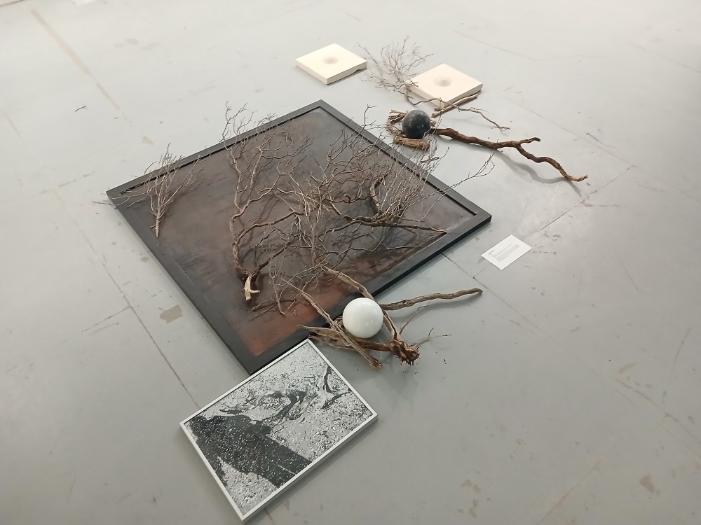 Installation : Peinture acrylique sur toile (100x100), sable, racines, éléments sculpturaux en marbre et pierre de Lecce.

Une quête qui commence par la reconstruction de l'histoire familiale et se transforme en recherche d'identité, à la fois formelle et matérielle : des racines brisées, mais aussi la terre et la pierre qui symbolisent le lien profond avec ses origines et, en même temps, le désir de reconstruire et de retrouver stabilité et équilibre.