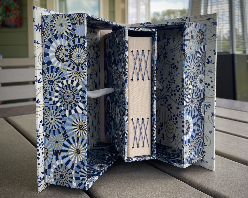 This is a Pop Up Box, a structure I learned from Nancy Akerly of Liberty Grove Paper Arts. When you open the box, a book pops out from the center box.  It’s so cute and very clever!